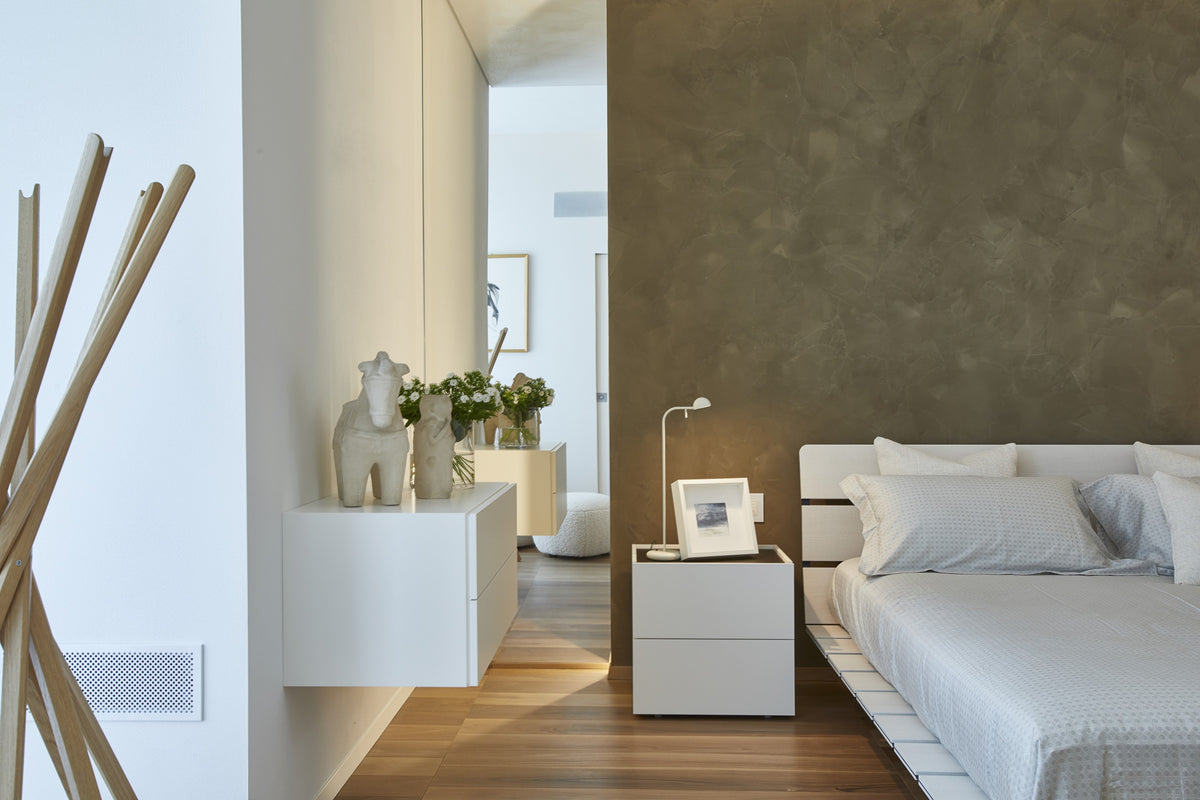 Camera da letto con parete materica, comodino sospeso e arredo minimale