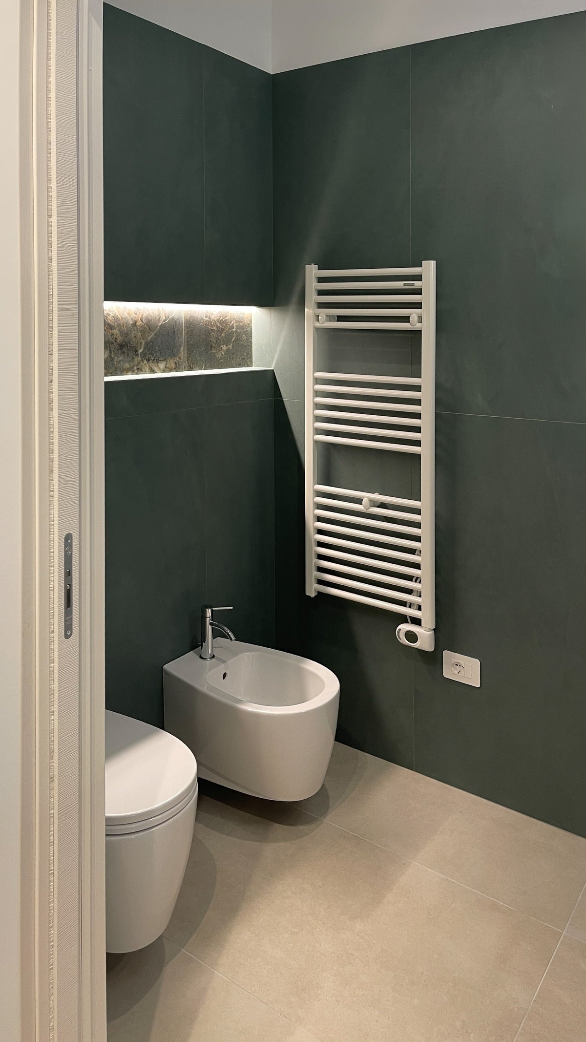 Bagno contemporaneo con rivestimenti verde scuro, sanitari sospesi e nicchia retroilluminata