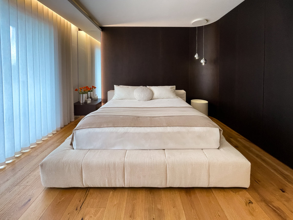 Vista frontale della camera padronale con letto imbottito e rivestimento su misura in legno scuro