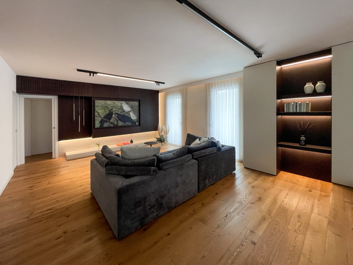 Progetto d’arredo su misura della zona giorno con grande divano, parete TV attrezzata e libreria integrata illuminata