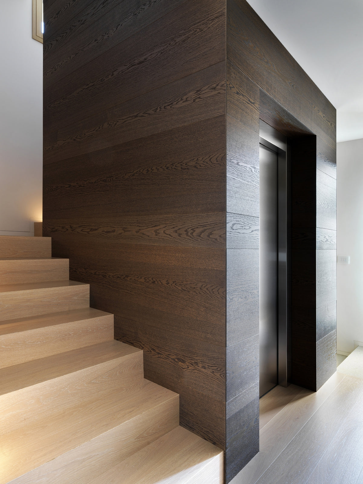 Scala interna con rivestimento in legno a due toni e ascensore privato
