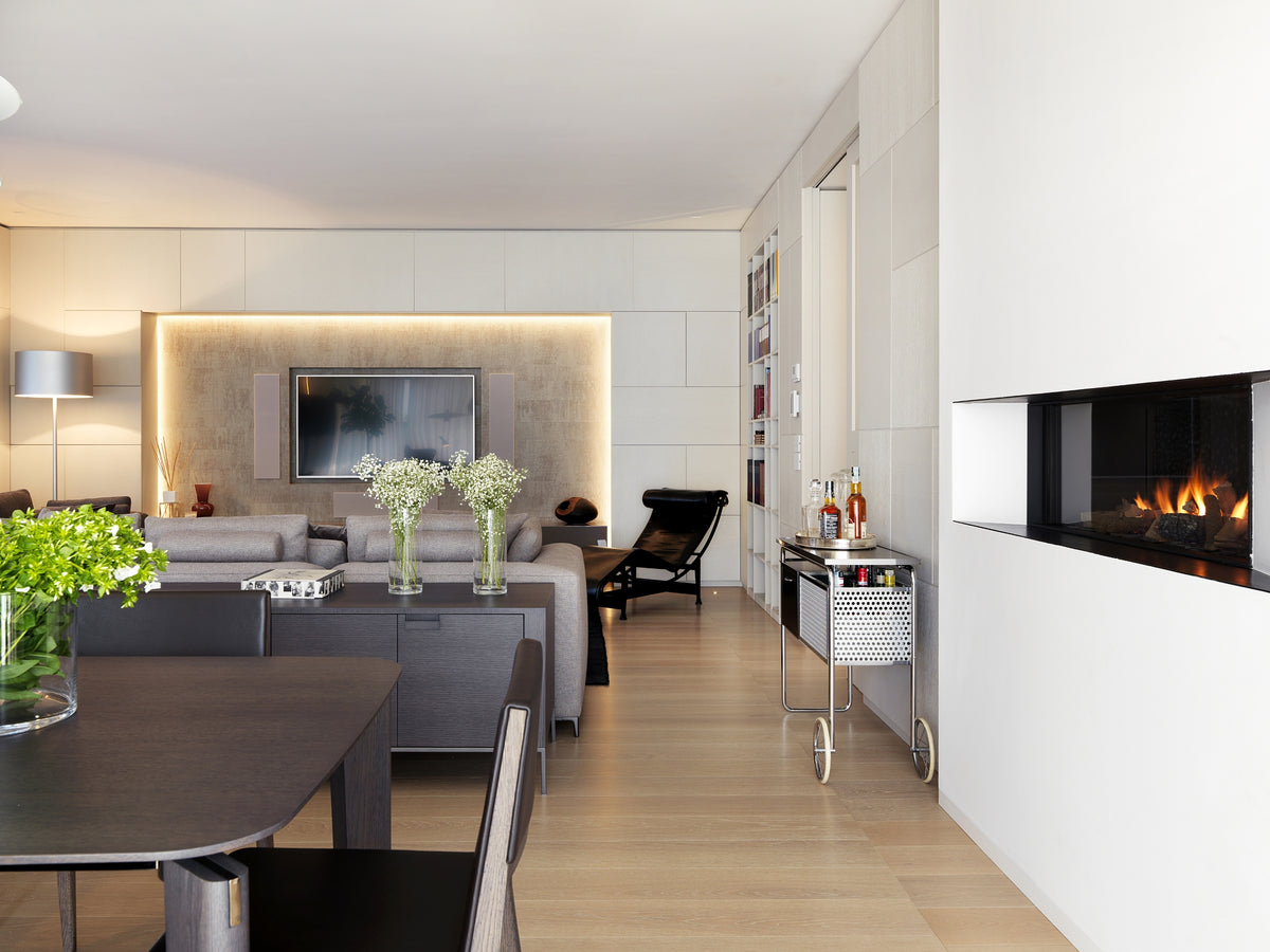 Soggiorno open space con divani modulari, chaise longue di design, nicchia TV illuminata e libreria integrata a parete