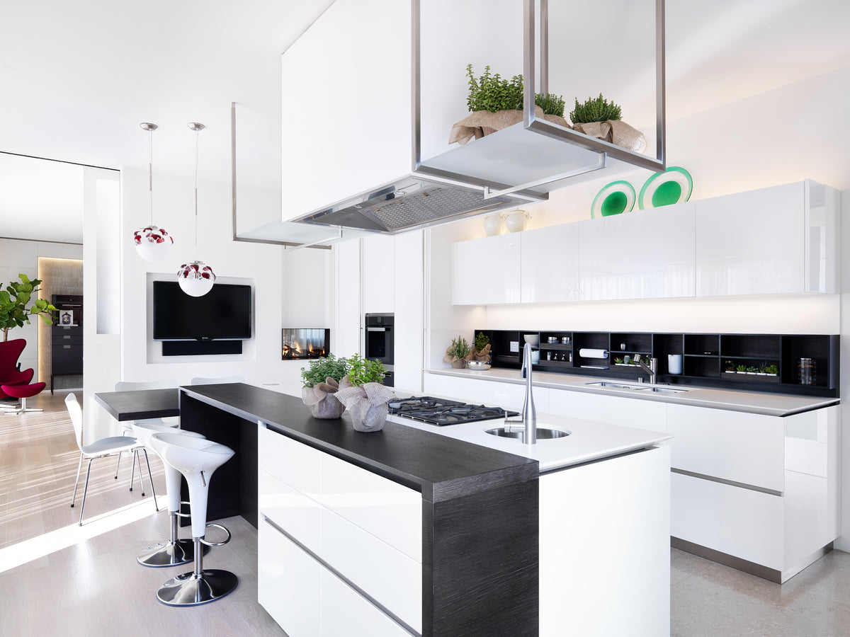 Cucina minimal bianca con isola centrale, piano snack in legno scuro e parete attrezzata su misura