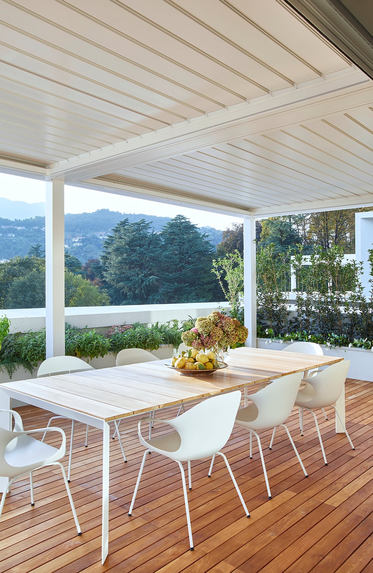 Terrazza coperta con tavolo da pranzo outdoor e pergola bioclimatica, affaccio sul paesaggio verde dall'attico