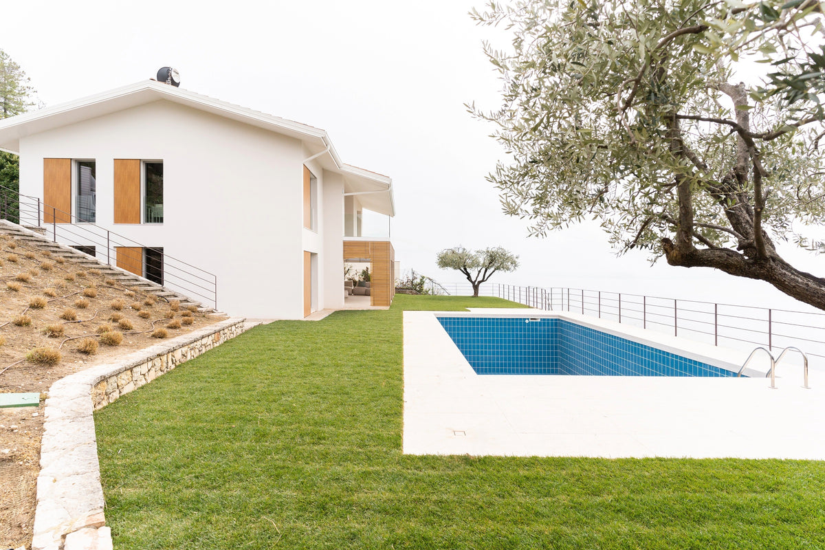 Vista esterna della villa con piscina, prato panoramico e facciata contemporanea