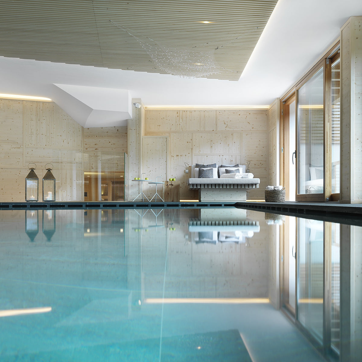 Area wellness con piscina, lettini e boiserie in legno naturale, progetto di interior design su misura per un hotel di lusso in Alto Adige