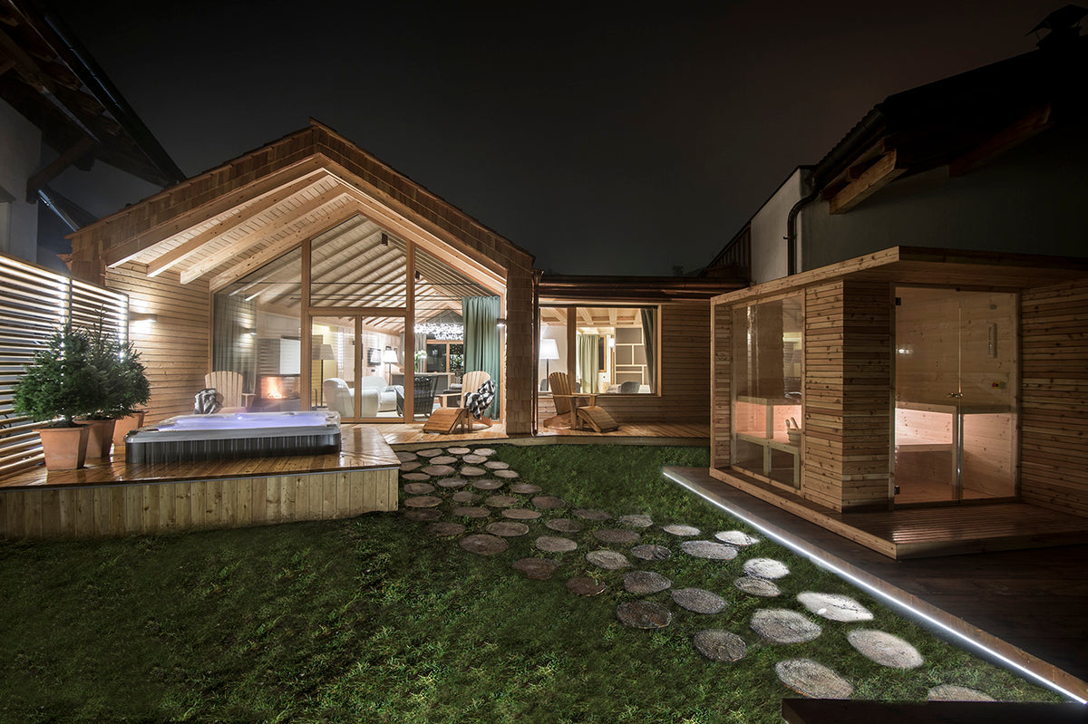 Vista notturna dello chalet in legno, nuova costruzione a San Cassiano, con zona relax, grandi vetrate e sauna esterna