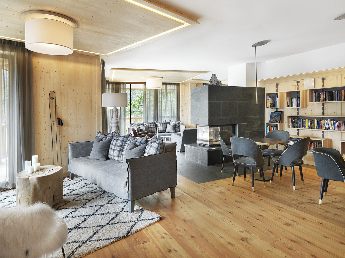 Lounge di hotel di lusso in stile alpino, con libreria, camino e progettazione su misura in legno chiaro