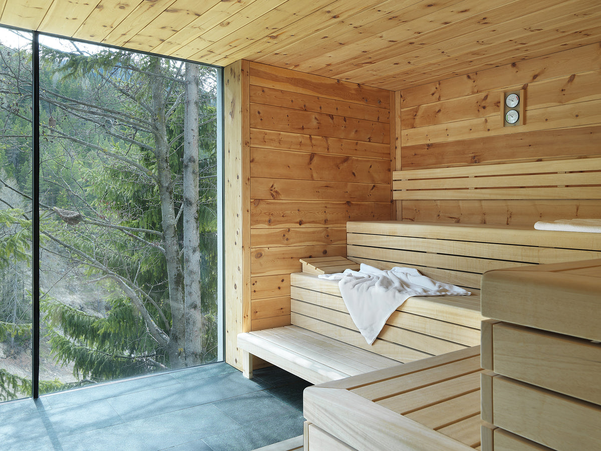 Sauna in legno con grande finestra sul bosco e atmosfera raccolta, in hotel di lusso 5 stelle in Alto Adige