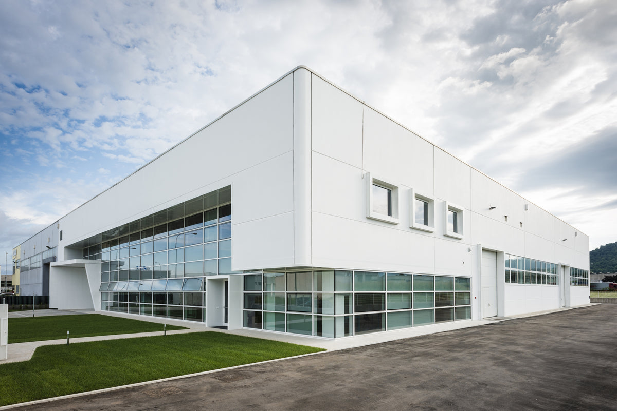 Vista angolare della sede direzionale con volumi puliti e vetrate continue, progetto contract contemporaneo