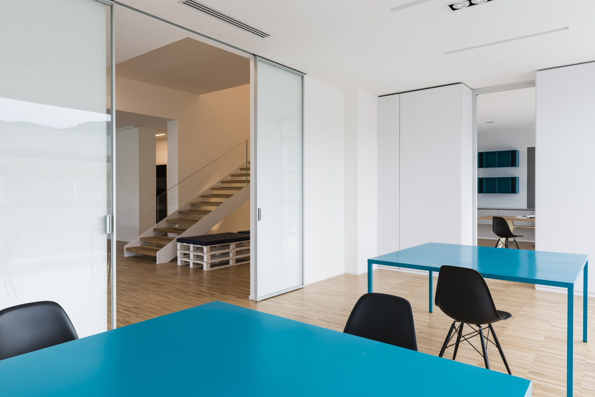 Area operativa con tavoli colorati e sedute nere, spazio di lavoro condiviso con interior design funzionale