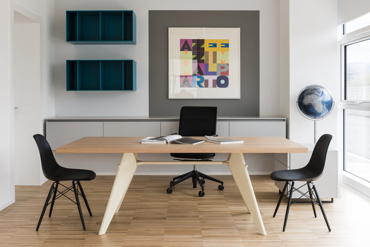 Postazione di lavoro con scrivanie in legno e sedute scure, con parete attrezzata con mobili sospesi e opera d'arte contemporanea