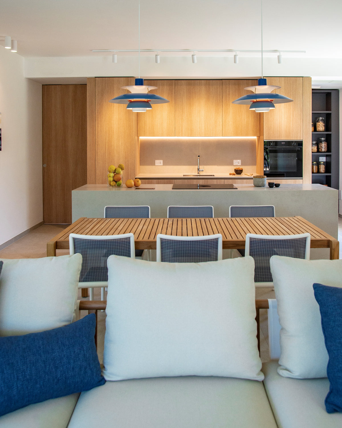 Dettaglio frontale dell’open space con living, tavolo da pranzo e cucina su misura in legno