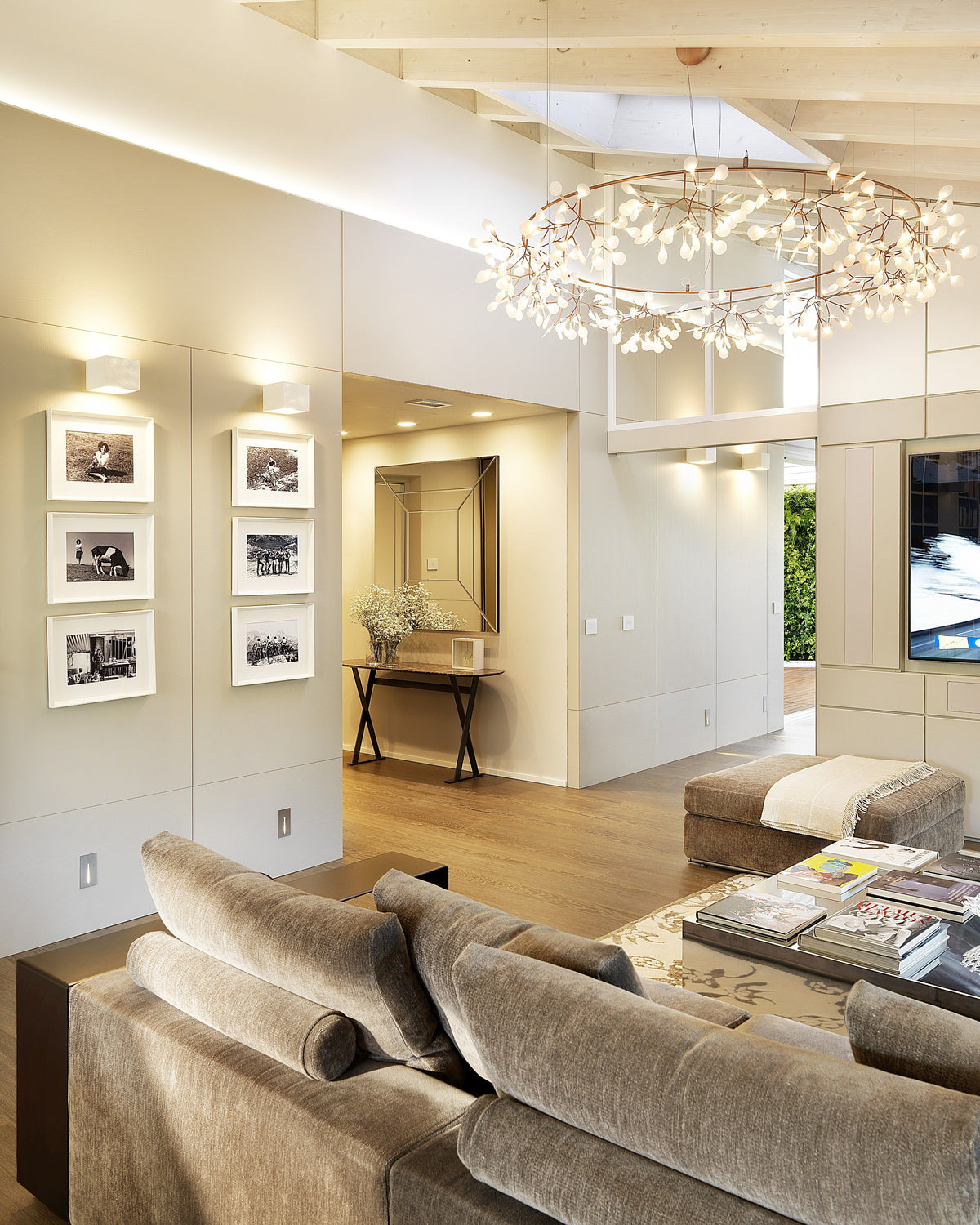 Dettaglio del living con divano modulare, boiserie neutra e lampadario scenografico