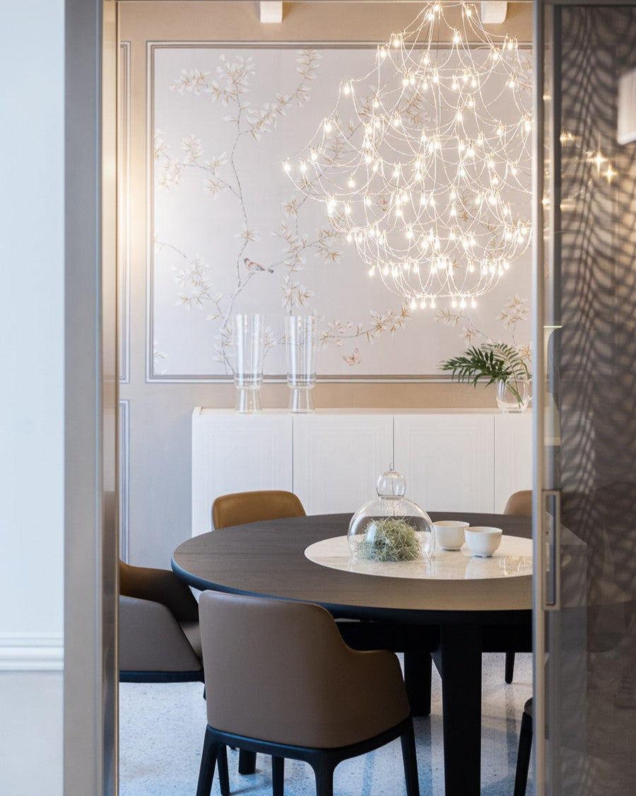 Dettaglio della sala da pranzo con tavolo rotondo, parete decorativa floreale e lampadario chandelier 