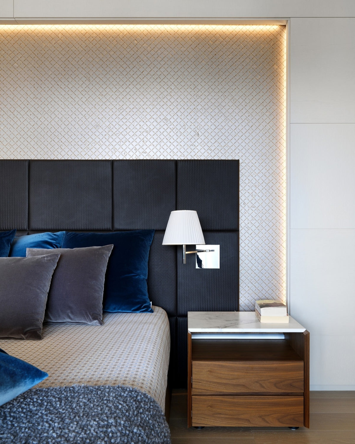 Dettaglio camera da letto con nicchia, illuminazione integrata, carta da parati decorativa e arredo su misura