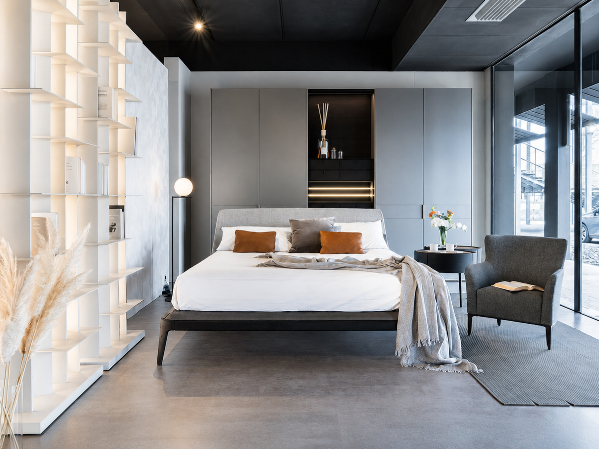 Camera da letto contemporanea nello showroom Cariolato a Cornedo Vicentino, con letto imbottito, armadiature su misura e libreria bianca