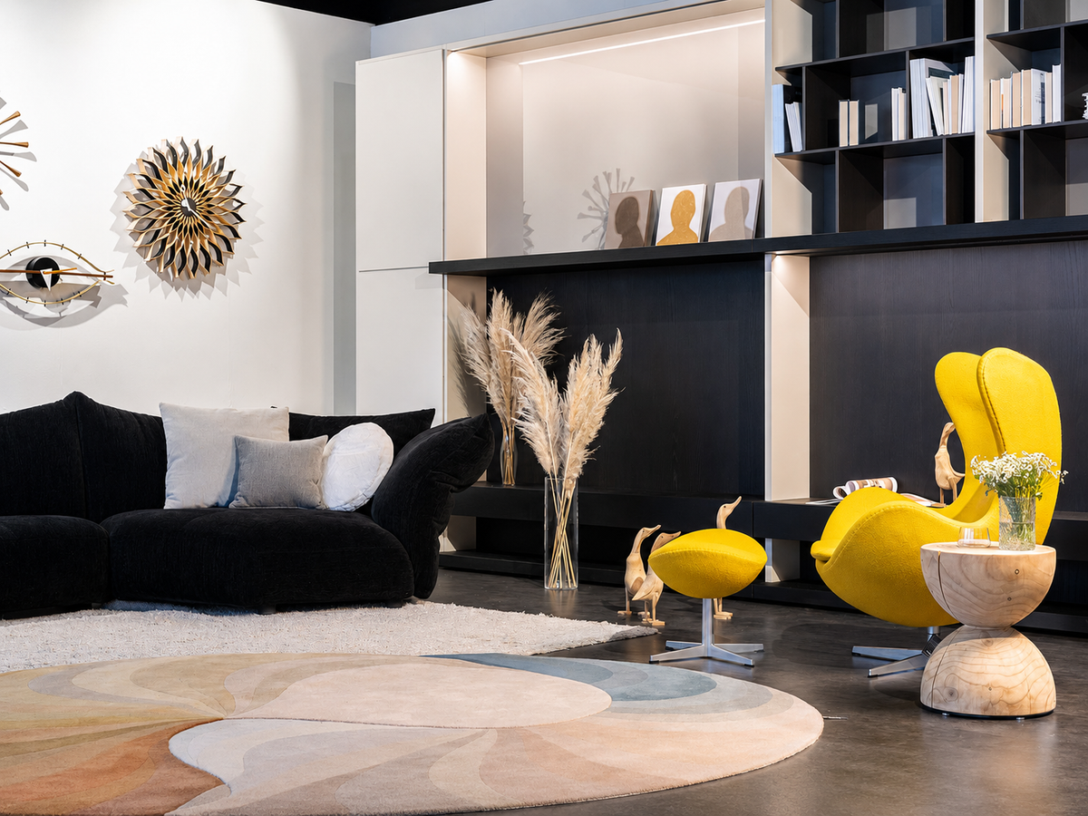Living di design nello showroom Cariolato a Cornedo Vicentino con divano nero, poltrona gialla, libreria a parete e tappeto decorativo